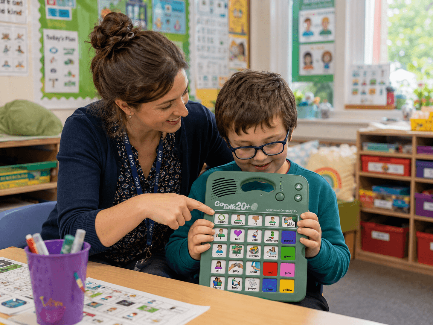Teacher and student in a classroom with a GoTalk 4+ Lite Touch communication device