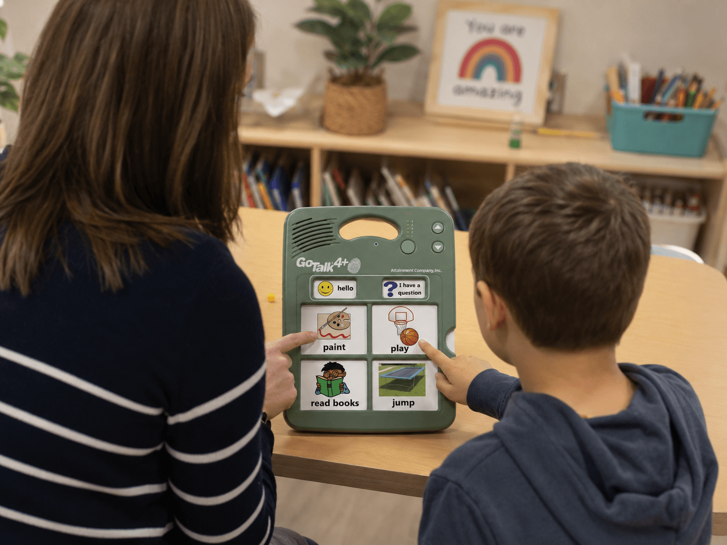 Teacher and student using a GoTalk 4+ Lite communication device in a classroom setting